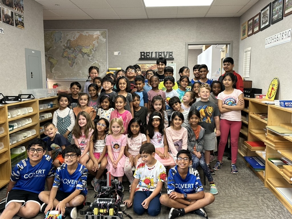 Covert Robotics team members with a classroom of young students and a competition robot